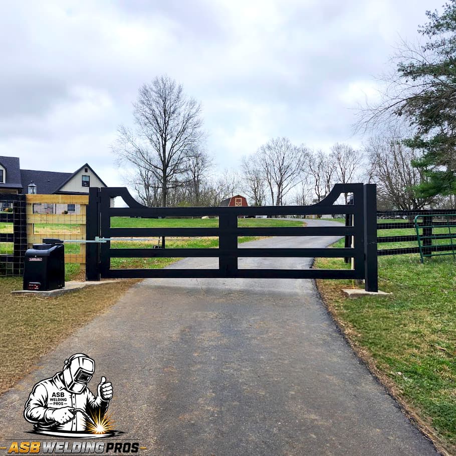 Black horizontal ranch-style driveway gate spanning a wide farm entrance.