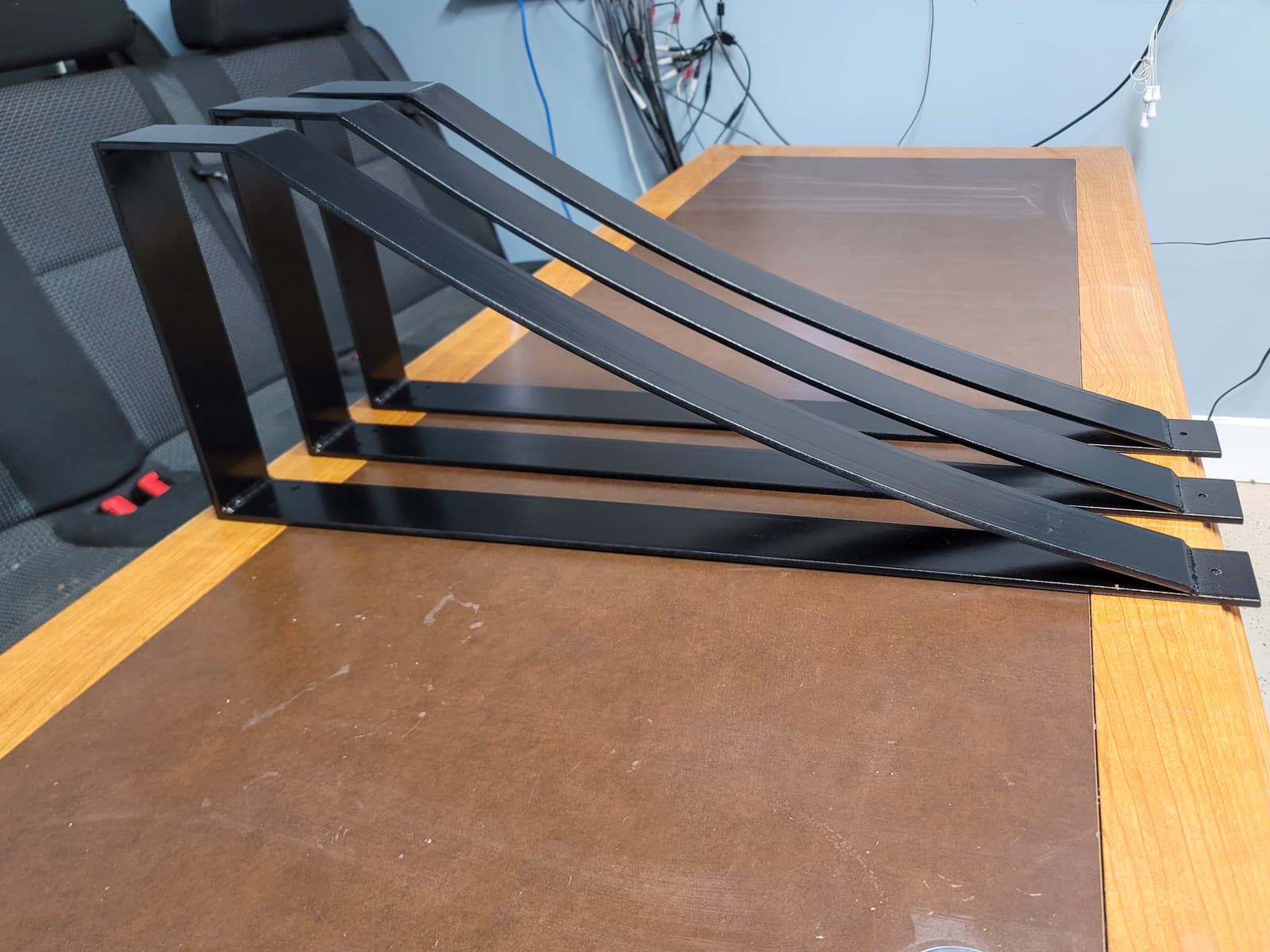 Custom fabricated steel brackets arranged on a workshop table.