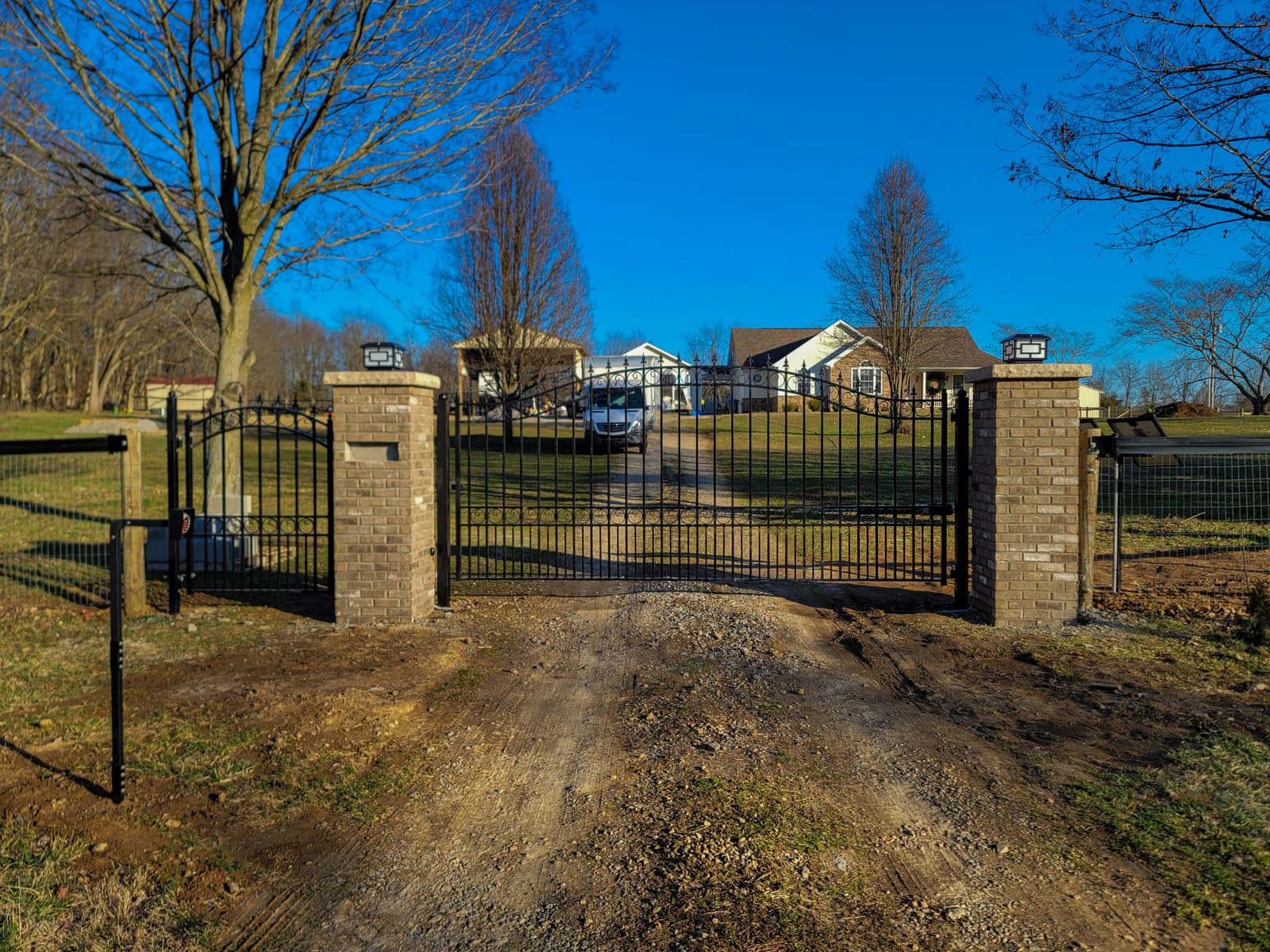 Ornamental black driveway gates between brick entrance columns.