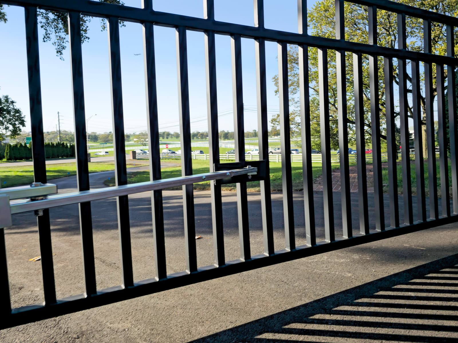 Finished black driveway gate beside a green lawn.