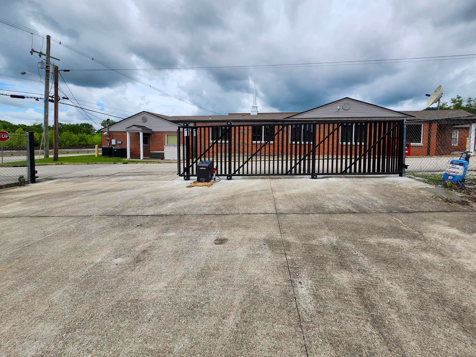 Black sliding metal gate at a brick commercial building.