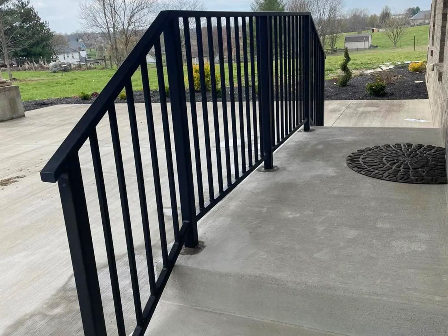 Finished porch railing installed along a residential walkway.