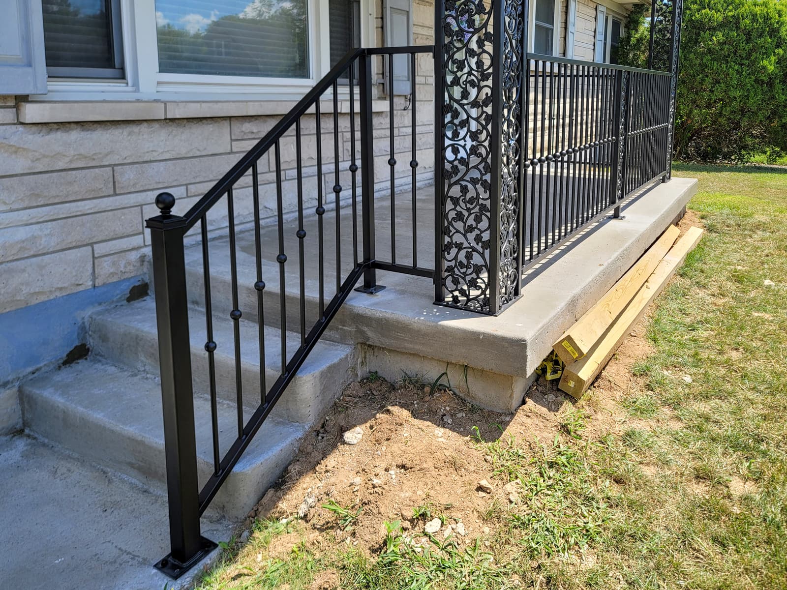 Black porch handrails and ornamental posts beside brick entrance steps.